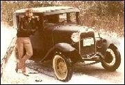 A photograph of the curator on a snowy winter day. He is leaning against his 1930 Model A Ford 4-door sedan while parked on a country lane.