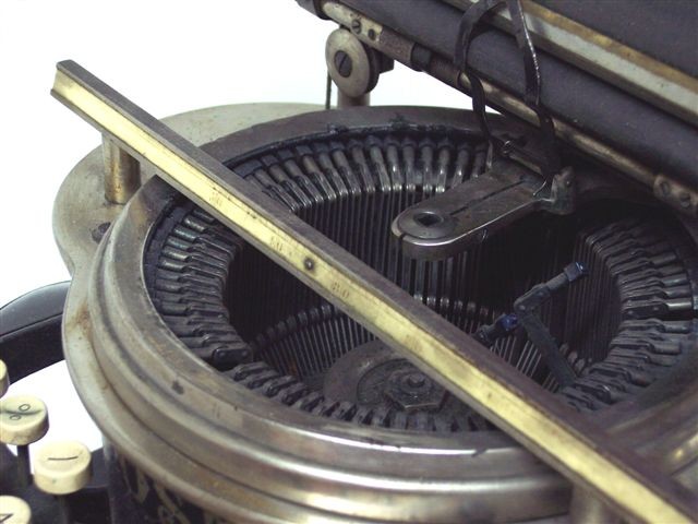 Here is a close-up of the type basket. One type bar is shown moving type into position below the hole in the flat alignment piece.